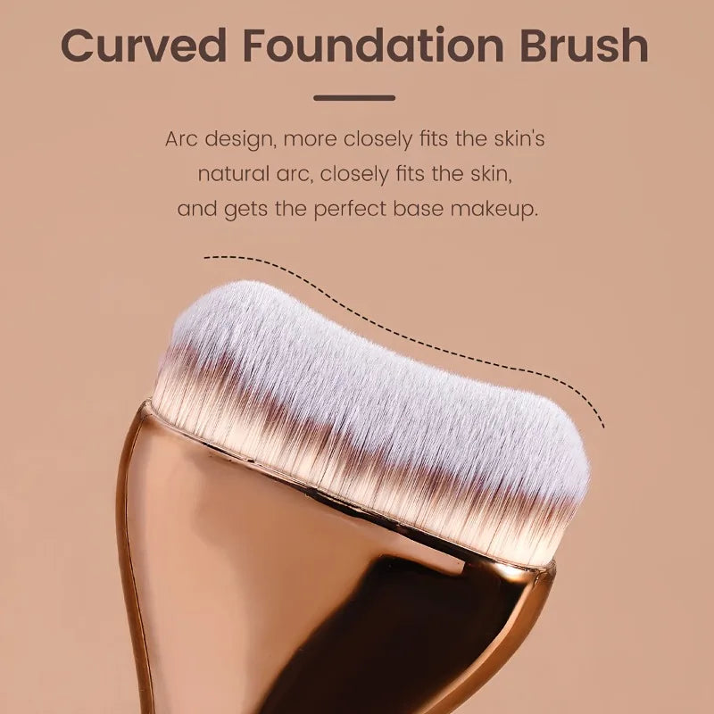 A close-up of a curved foundation brush with soft nylon bristles shown against a neutral background.