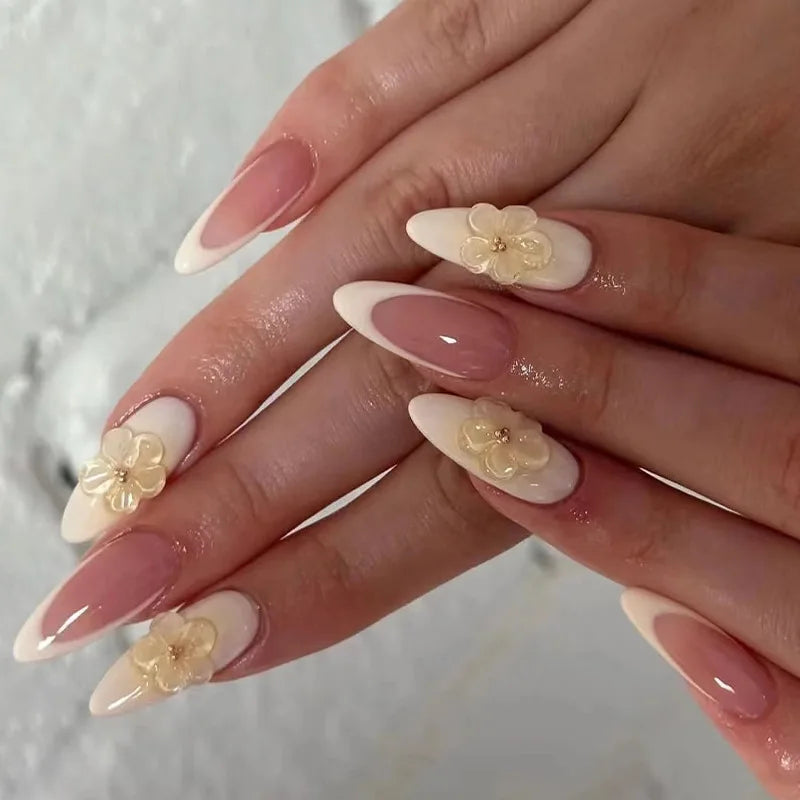 A hand displaying a set of 24 press-on almond nails featuring delicate floral and butterfly designs.