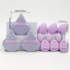 A set of 12 purple makeup sponges in various shapes and sizes displayed on a white surface.