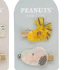 A set of Peanuts hair clips featuring a yellow hand and a pink face design.