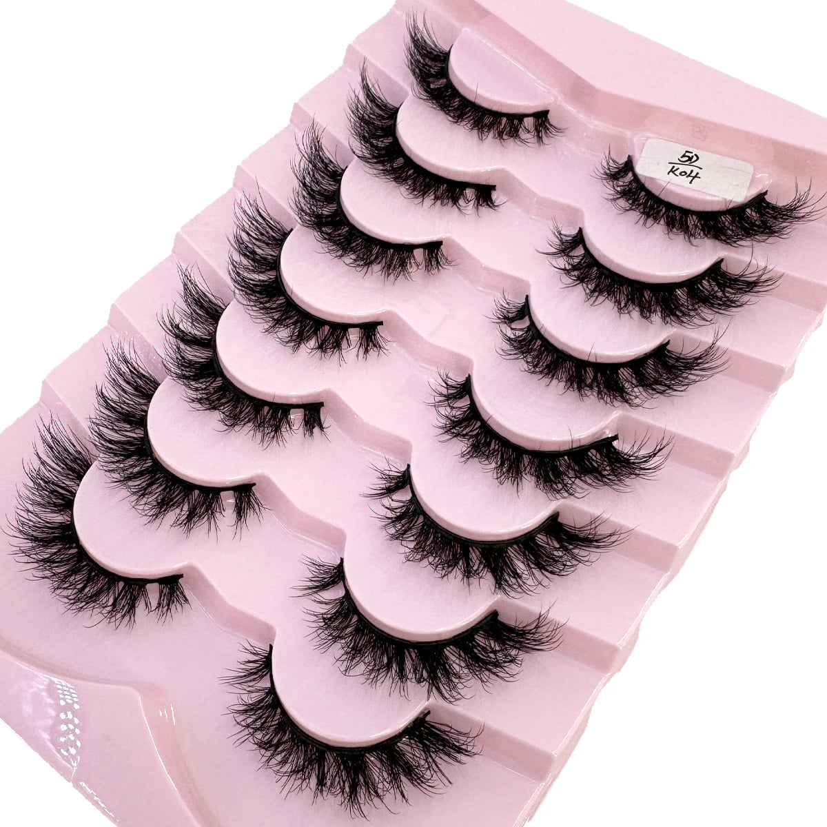 Plateau en plastique rose contenant divers styles de faux cils de renard noirs pour usage cosmétique.