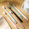 A collection of soft bristle toothbrushes in various pastel colors, including pink, mint green, and white, displayed on a woo