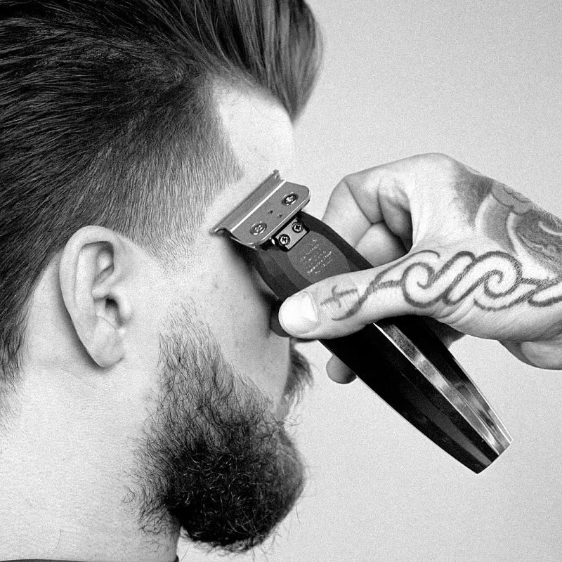 A hand is using a professional electric hair trimmer kit to style a beard.