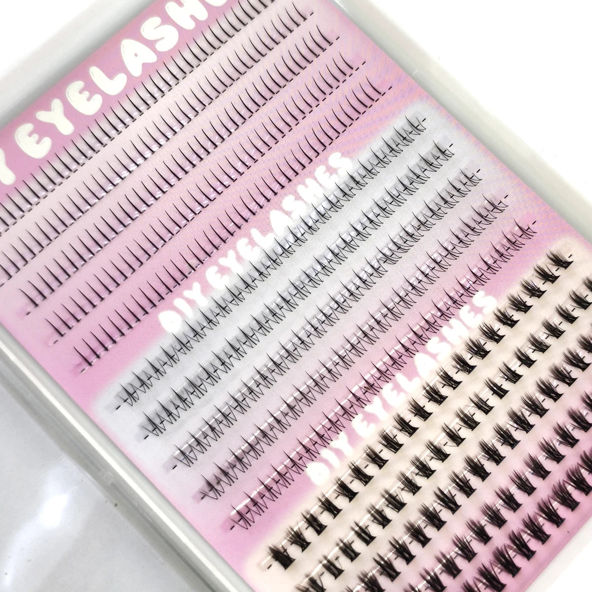 A close-up of DIY Wispy Extension Eyelashes showing various lash styles and lengths on a pink background.