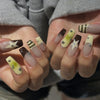 A close-up of hands displaying press-on nails with a mix of brown, beige, and yellow accents featuring star designs.
