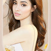A woman models a long, wavy brown hairstyle while holding a hair stick product.