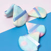 A set of triangular cosmetic powder puffs in pastel blue and pink with light purple ribbon ties.