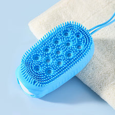 A bright blue silicone body brush with textured bristles rests on a white towel.