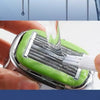 A hand is using a precision manual safety razor with a green handle and silver blades for shaving.
