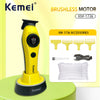 A yellow Kemei brushless motor hair clipper with a black base and accessories displayed on a light green surface.