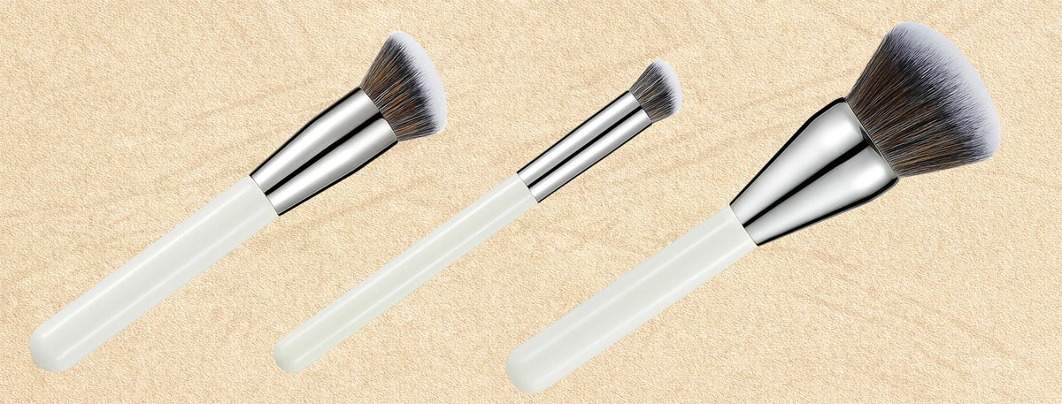 A set of three professional makeup brushes with silver ferrules and fluffy bristles shown against a light background.