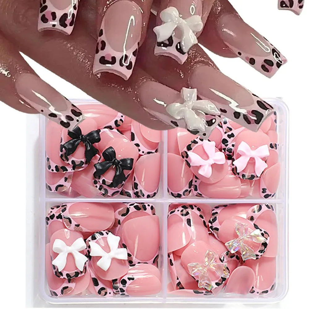 A hand displays leopard print press-on nails and a set of pink and black accent nails in a clear plastic container.
