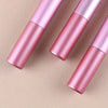 A set of three pink makeup brushes displayed diagonally on a neutral background.
