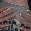 A close-up of a hand displaying red and pink striped press-on almond shaped nails on a person's fingers.