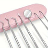 A set of professional multi-tool tooth cleaning instruments with silver tips and a pink holder.