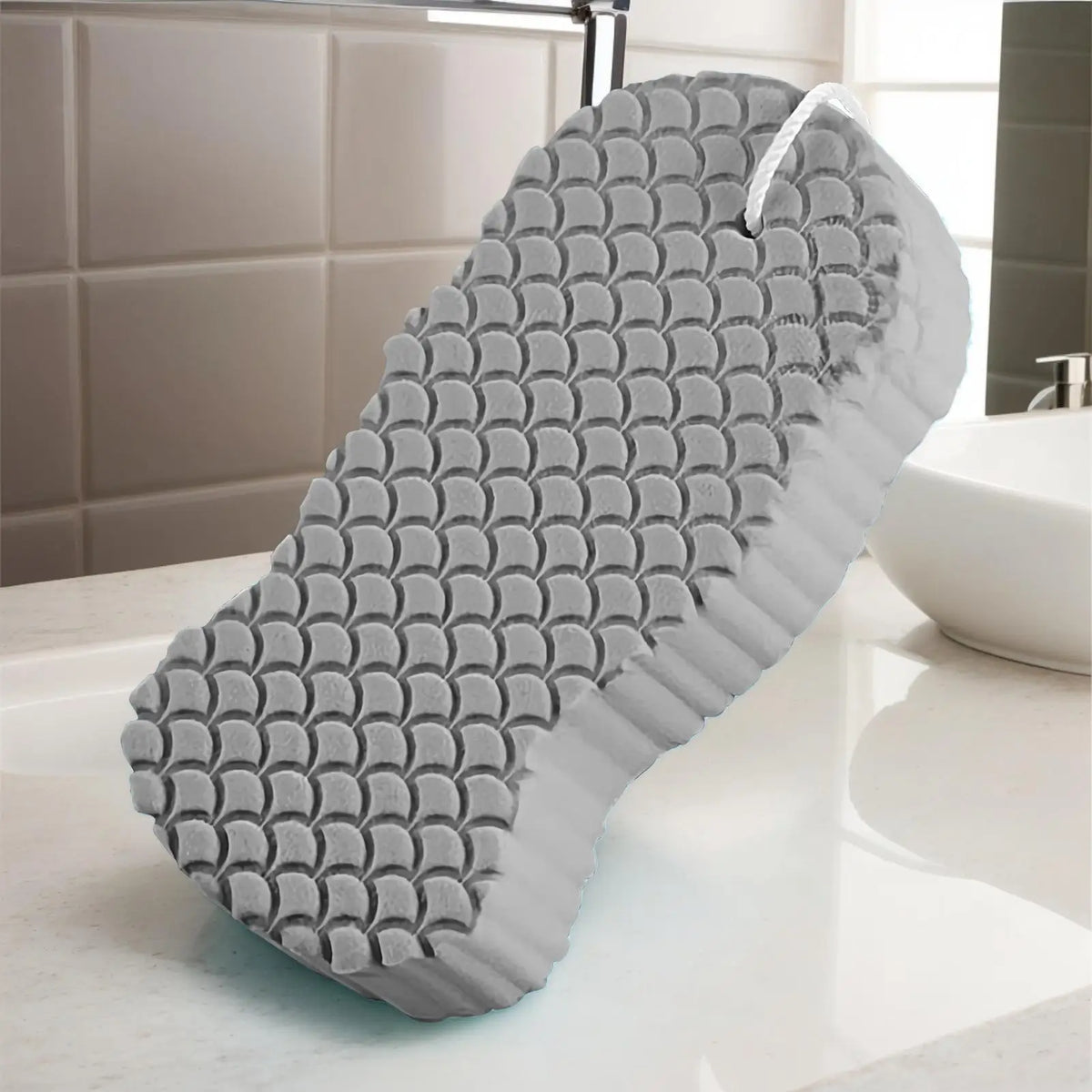 A gray exfoliating bath sponge set with a textured surface is displayed on a white countertop.