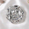 A vintage rose design double-sided pocket makeup mirror with a silver finish resting on a white satin fabric.