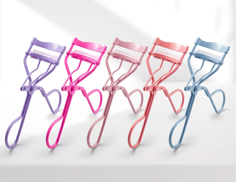 A row of five precision eyelash curlers in purple, pink, and blue are displayed on a white surface.