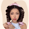 Une femme modèle un accessoire pour cheveux rose et un kit d'outils de coiffure sur ses cheveux foncés.