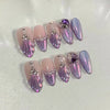 Un ensemble de 24 ongles press-on roses français à l'amande avec des accents de paillettes violette iridescente et argentée.