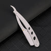 A silver manual straight edge shaver kit lying on a dark textured surface.