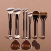 A set of seven professional makeup brushes in various sizes and shades displayed against a neutral background.