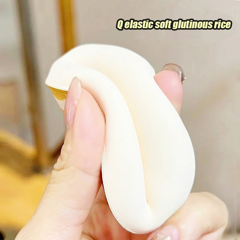 A hand holds a white elastic soft glutinous rice makeup puff.