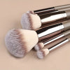 A set of makeup brushes with silver handles and fluffy, light beige bristles.