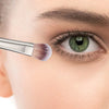 A precision makeup brush is shown applying product to an eye for detailed cosmetic application.