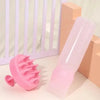 Un peigne applicateur de teinture capillaire en silicone rose à côté d'un bloc orange et d'une clôture en piquets blancs.