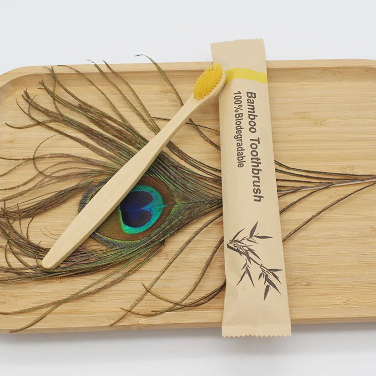 A bamboo toothbrush packaged in a paper sleeve rests on a wooden cutting board with a feather design.