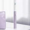A purple sonic electric toothbrush standing upright next to a purple case.