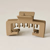A beige non-slip hat claw clip with multiple teeth for securing baseball caps.