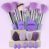 A collection of ten professional makeup brushes in various shades of purple and lilac, displayed on a light-colored box.