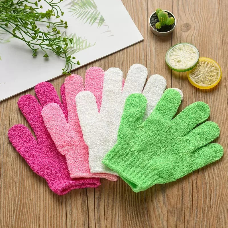 Une collection de cinq gants exfoliants pour le corps roses, blancs et verts sont présentés sur une surface en bois.