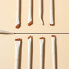 A set of precision angled eyeliner and eyebrow makeup brushes with white and wooden handles displayed vertically.