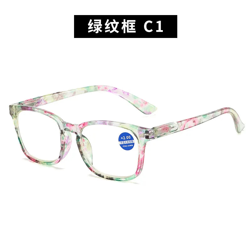 Pair of green and pink patterned reading glasses with clear frames.