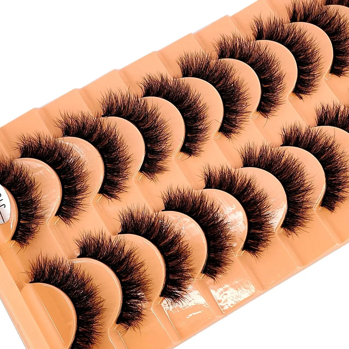 Un plateau de faux cils de renard faits main dans une couleur pêche ou nude.