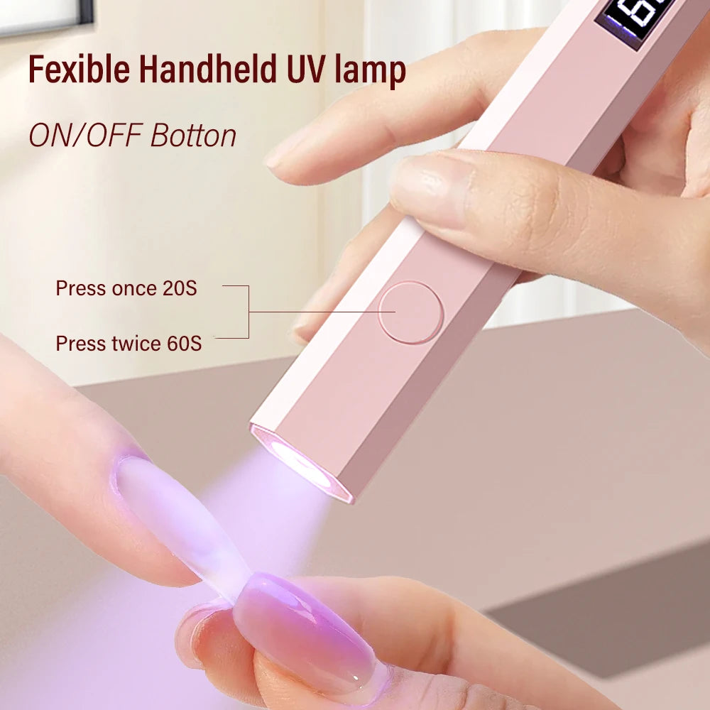 A hand is pressing a button on a pink handheld UV lamp to activate it, emitting purple light.