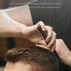 La mano de un hombre usa un peine plegable de acero de precisión en su cabeza para peinar su cabello.