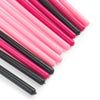 Una colección de brochas desechables para pestañas en rosa y negro dispuestas en diagonal sobre un fondo blanco.