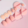 A set of twelve pink makeup sponges in various shapes and sizes arranged on a white surface.