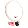 A pink portable dual-sided makeup mirror showing a 30X magnification setting.