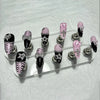 A set of press-on nails featuring black, pink, and zebra print designs with glitter diamonds.