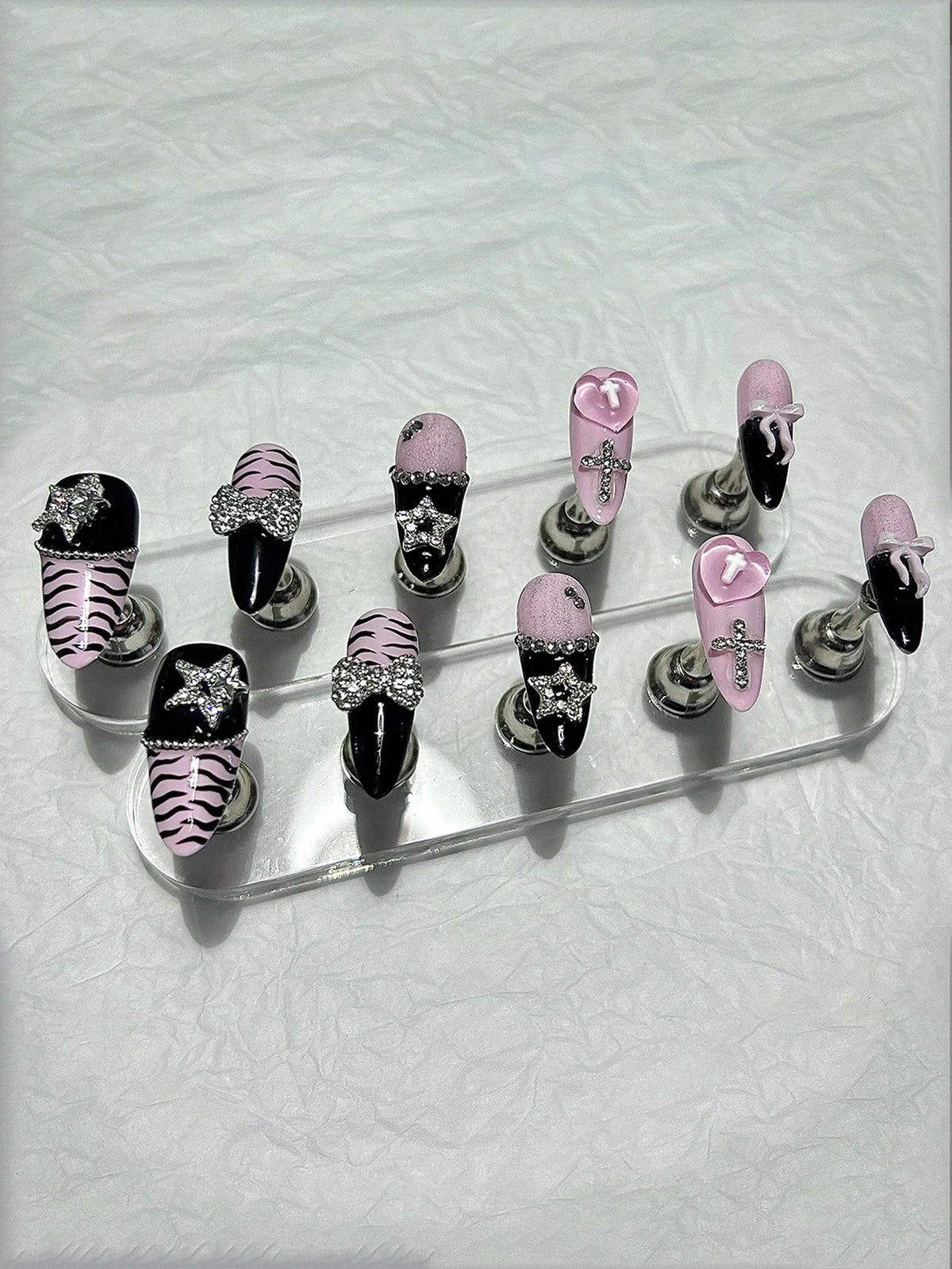 A set of press-on nails featuring black, pink, and zebra print designs with glitter diamonds.