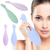 A woman is holding several silicone gua sha rollers of various shades, including green, purple, and blue, near her face for f