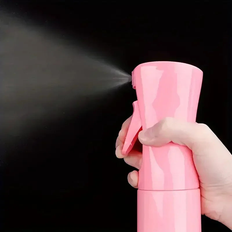 A hand holds a pink hair styling brush set and spray bottle, demonstrating the product's spray function against a dark backgr
