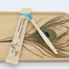 A bamboo toothbrush is shown next to a wooden cutting board with dried plant material.