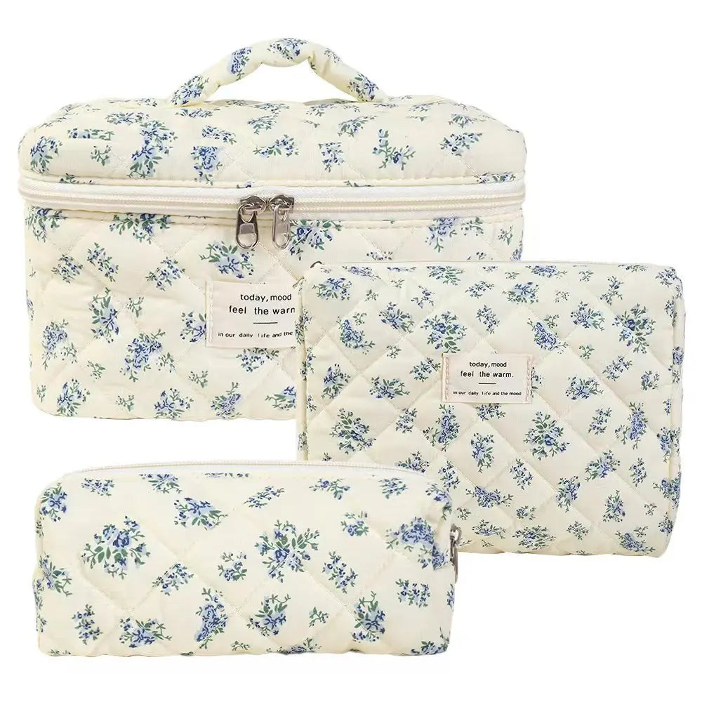 A set of three quilted cotton makeup bags featuring a white background with blue floral patterns.