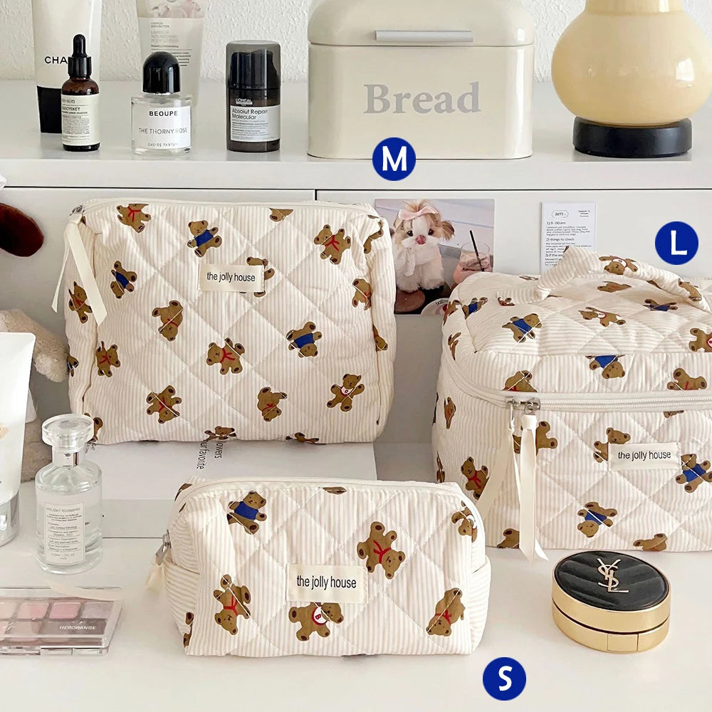 A collection of quilted cotton makeup bags and a bread box displayed on a white shelf.